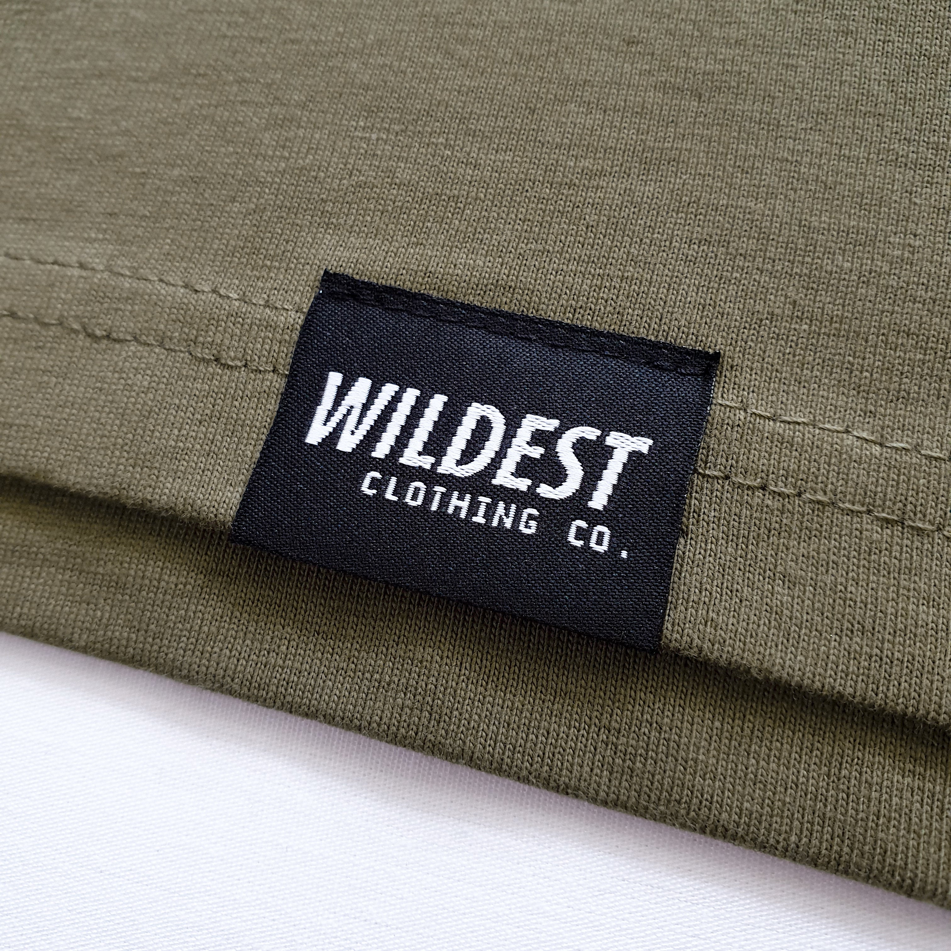 Close up of Wildest Clothing Co. brand tag on the bottom hem